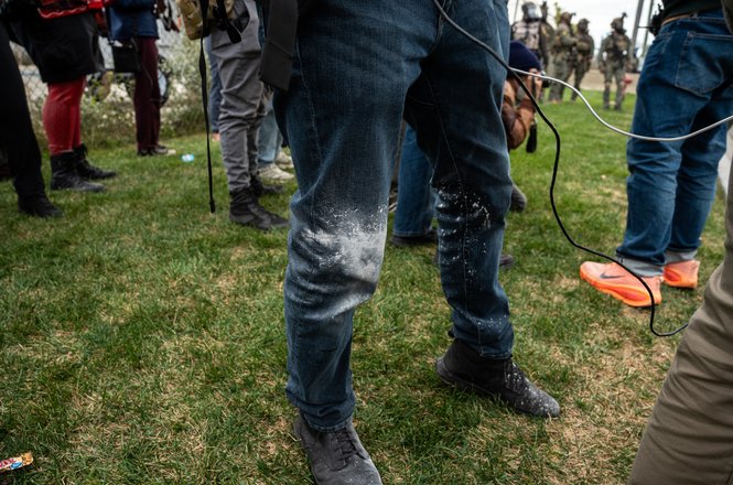 Photojournalist Jon Farina, his legs visible at center, was filming for Status Coup when an Illinois State Police trooper shot him in the knee and foot with pepper balls amid protests outside a federal immigration facility in Broadview on Nov. 1, 2025.