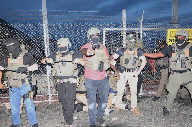 An Immigration and Customs Enforcement officer, in red at center, pepper-sprays photojournalist Cristina Panagi while she covers an immigration protest outside a detention facility in Newark, New Jersey, on May 26, 2026.