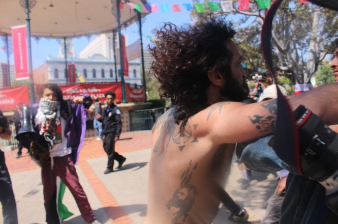 A far-right activist punches independent photographer Jonny Morales, whose arm and camera are visible in the frame, during a political protest outside City Hall in Los Angeles, California, on July 10, 2026.