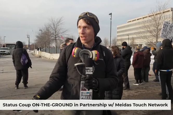 Status Coup reporter JT Cestkowski, center, livestreamed his coverage of immigration-related protests outside a federal building in Fort Snelling, Minnesota, on Jan. 11, 2026. He was shot with two pepper balls by federal officers later that evening.