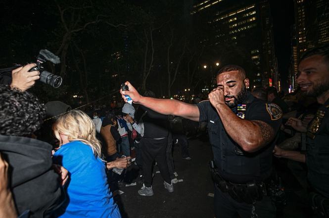 A police officer firing pepper spray at journalists and fans in New York City.