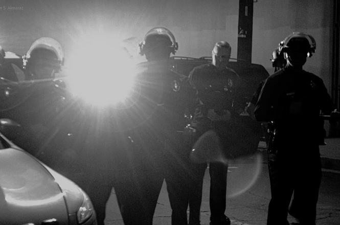 A Los Angeles police officer shines a light at photojournalist Cassandra Church, who was pushed by a sergeant while documenting a “No Kings” protest on Oct. 17, 2026.