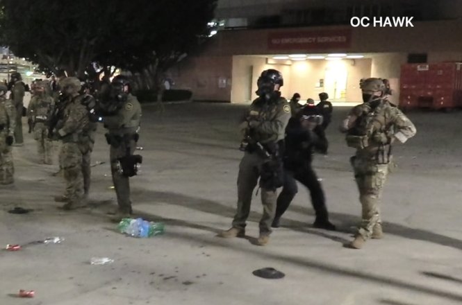 The image news photographer Mario Guerrero captured of a federal agent, crouching in black at right, pointing and shooting crowd-control munitions at him, breaking his finger, during an immigration protest on Jan. 31, 2026, in Los Angeles, California.