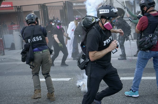 Journalists dodge a tear gas canister set off by federal agents at a demonstration in Los Angeles, California, on March 28, 2026