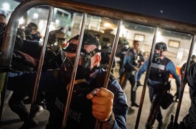 A New Jersey State Police officer pushes back protesters with a metal barricade outside an immigration detention center in Newark on May 30, 2026. Photojournalist Josh Pacheco was repeatedly hit with the barricade, damaging their camera lens.