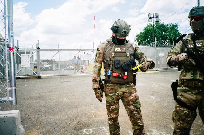 Federal officers with crowd-control weapons stand before an immigration detention center in Newark, New Jersey, on June 21, 2026. Journalist Wali Khan was covering protests outside the facility that day when an officer targeted him with pepper spray.