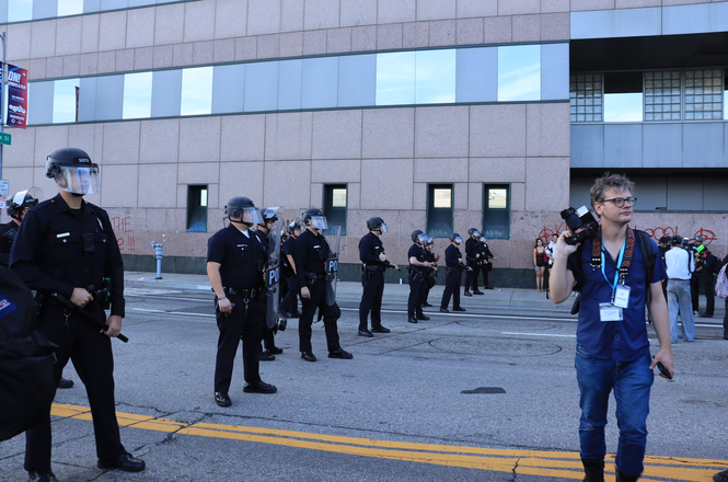 Police officers line up near media during a protest at LA’s immigration detention center on March 28, 2026