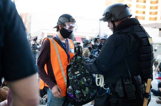 A member of the Sarpy County Sheriff’s Office searches the bag of Omaha World-Herald reporter Reece Ristau on June 1, 2020, in Omaha, Nebraska. (ANNA REED/OMAHA WORLD-HERALD) Ristau_search0601_floyd.JPG