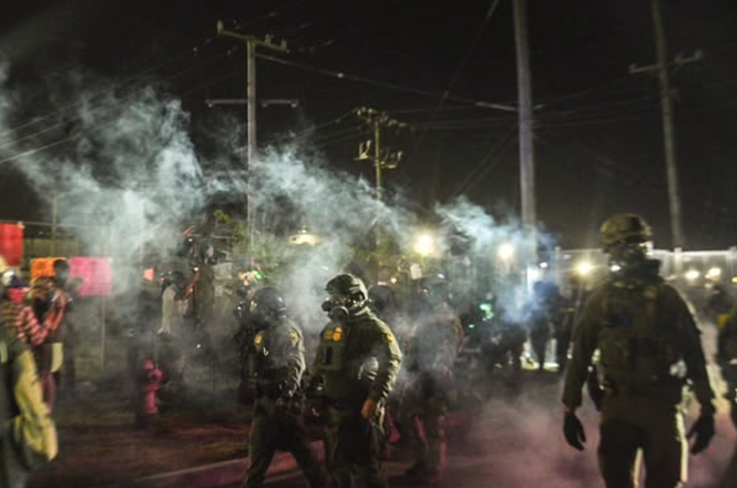 Federal agents amid tear gas at a protest in Broadview, Illinois, on Sept. 27, 2025. Photojournalist Jon Stegenga said he lost a telephoto camera lens during the demonstration.