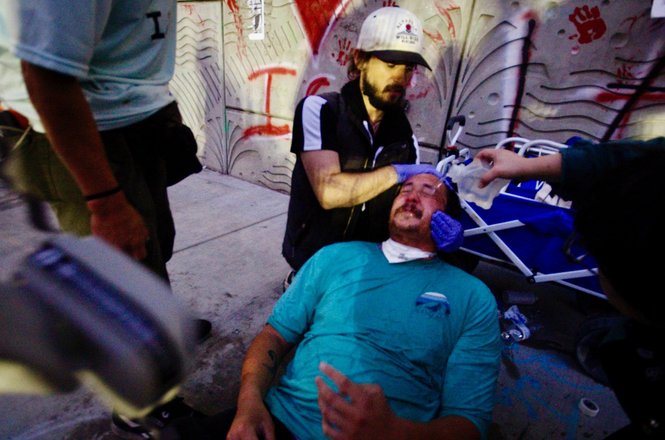 Photographer Benjamin Hanson, above in blue, gets his eyes washed out. He was pepper-sprayed by federal officers while documenting an immigration protest in Los Angeles, California, on Sept. 1, 2025.