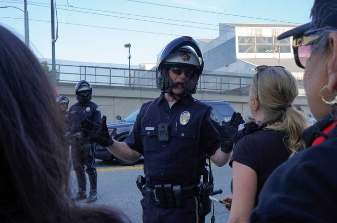 Status Coup reporter Tina-Desiree Berg, center right, confronts a police officer over the arrest of fellow journalist Lexis-Olivier Ray amid workers’ rights and immigration protests in Los Angeles, California, on May 1, 2026.